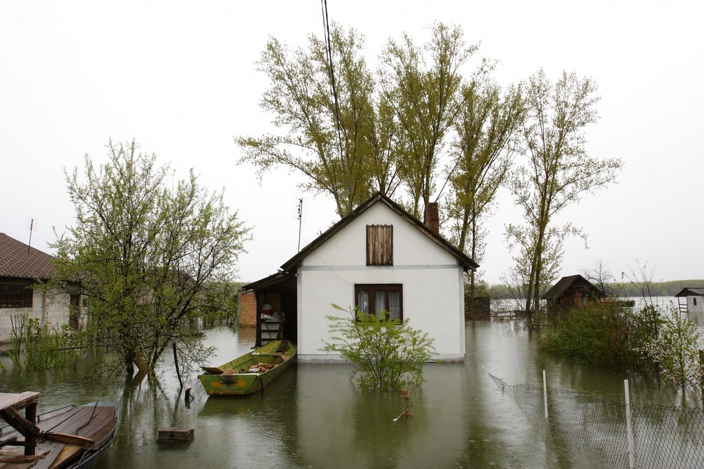 House with flooded area around it and boat next to it